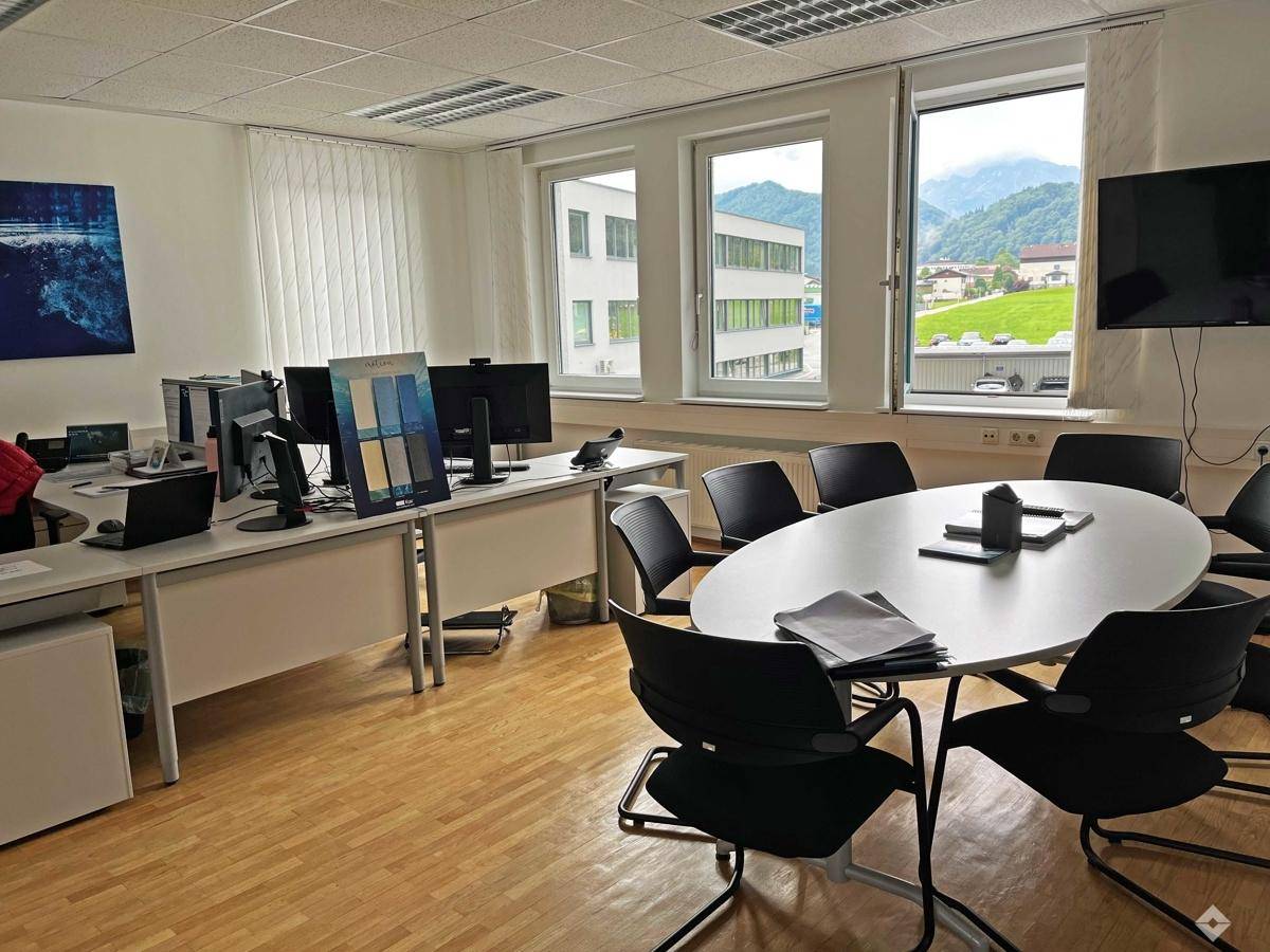 Modernes Büro mit Arbeitsplätzen, Besprechungstisch und Fenstern mit Blick auf die Umgebung.