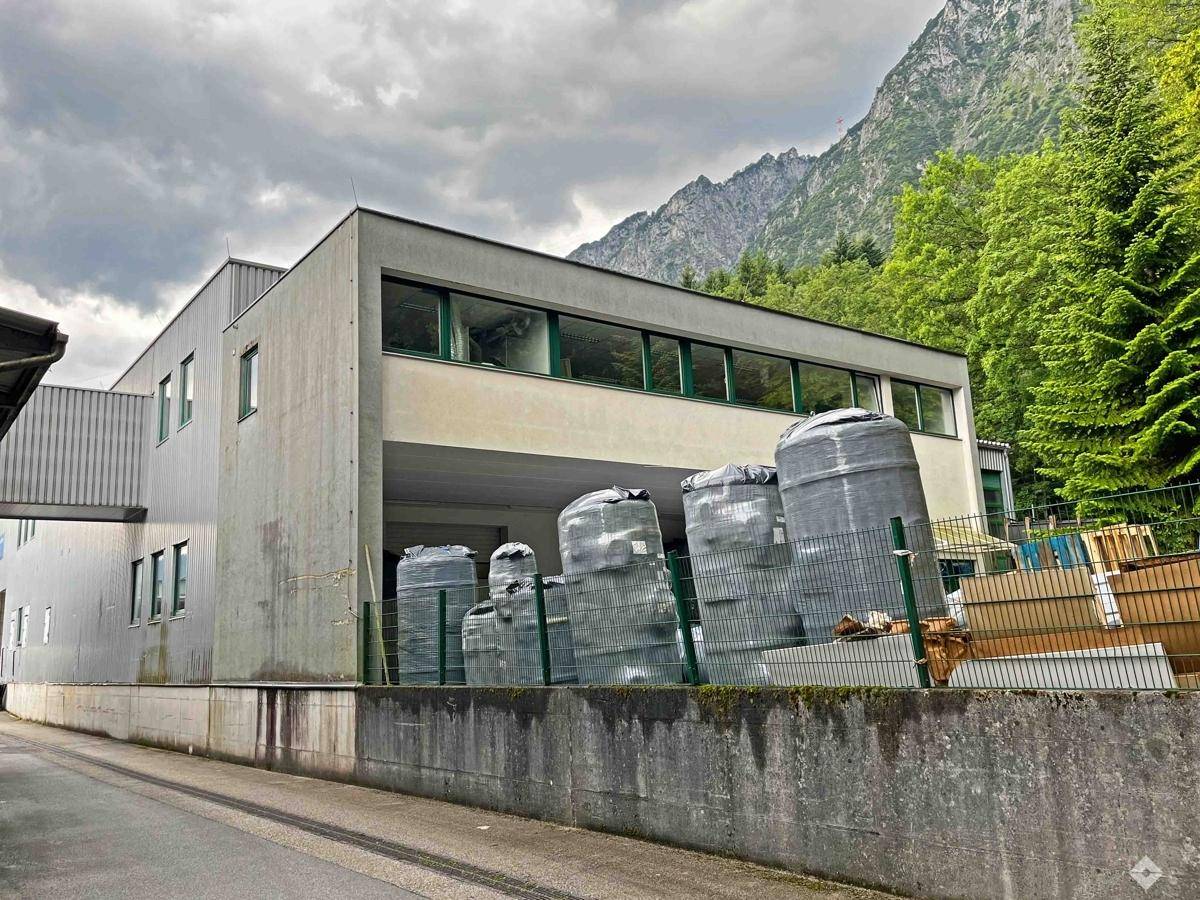 Industriegebäude mit Lagerbereich und Blick auf die umliegenden Berge und Wälder.