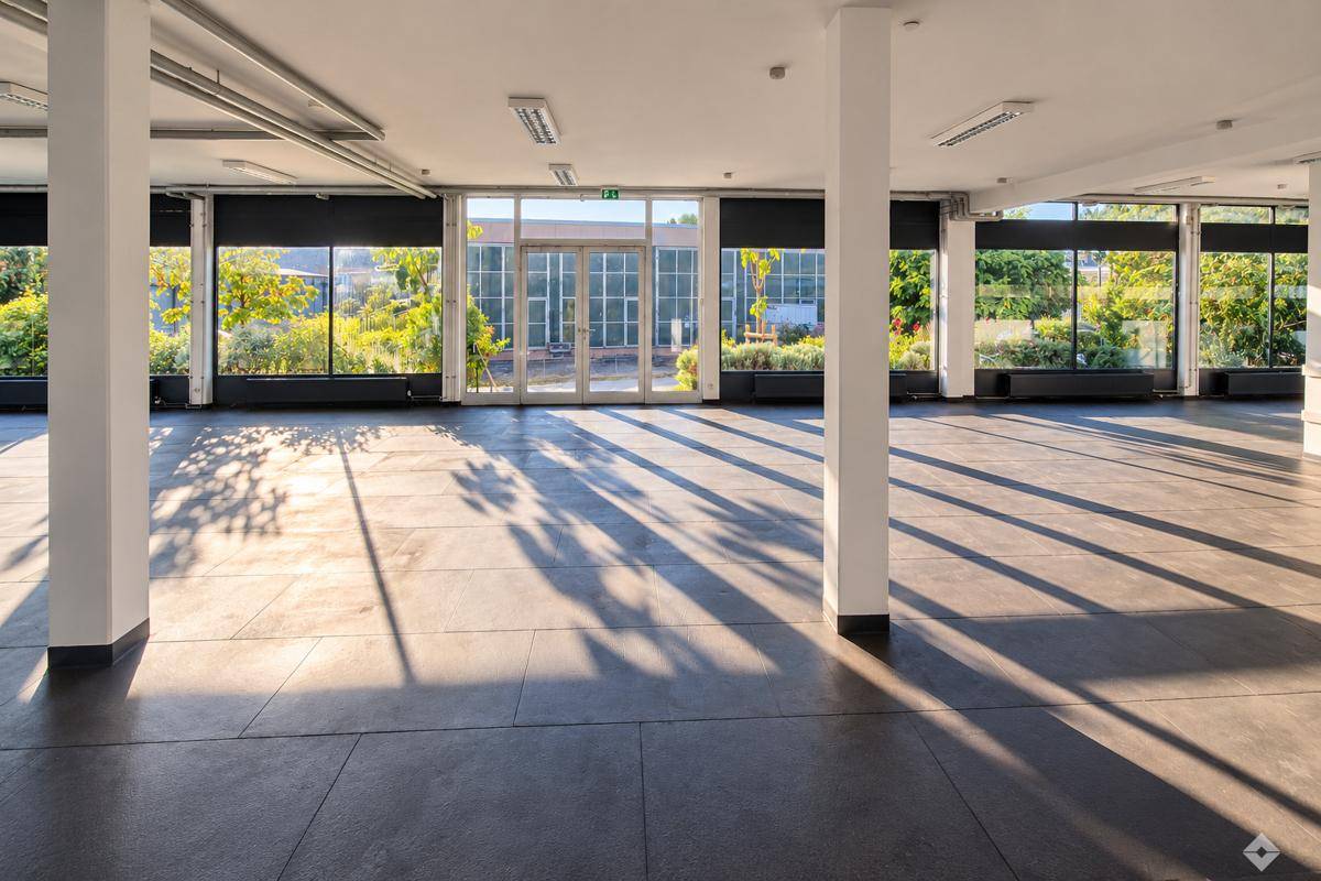 Heller, offener Bürobereich mit dunklem Fliesenboden und großen Fensterfronten, die viel Sonnenlicht hereinlassen.