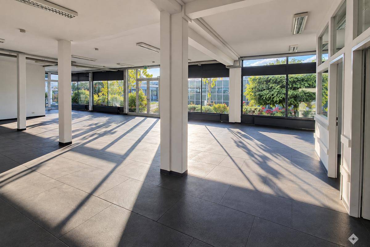 Großer, flexibler Büroraum mit Säulen und durchgehenden Fensterfronten, die einen Blick ins Grüne ermöglichen.