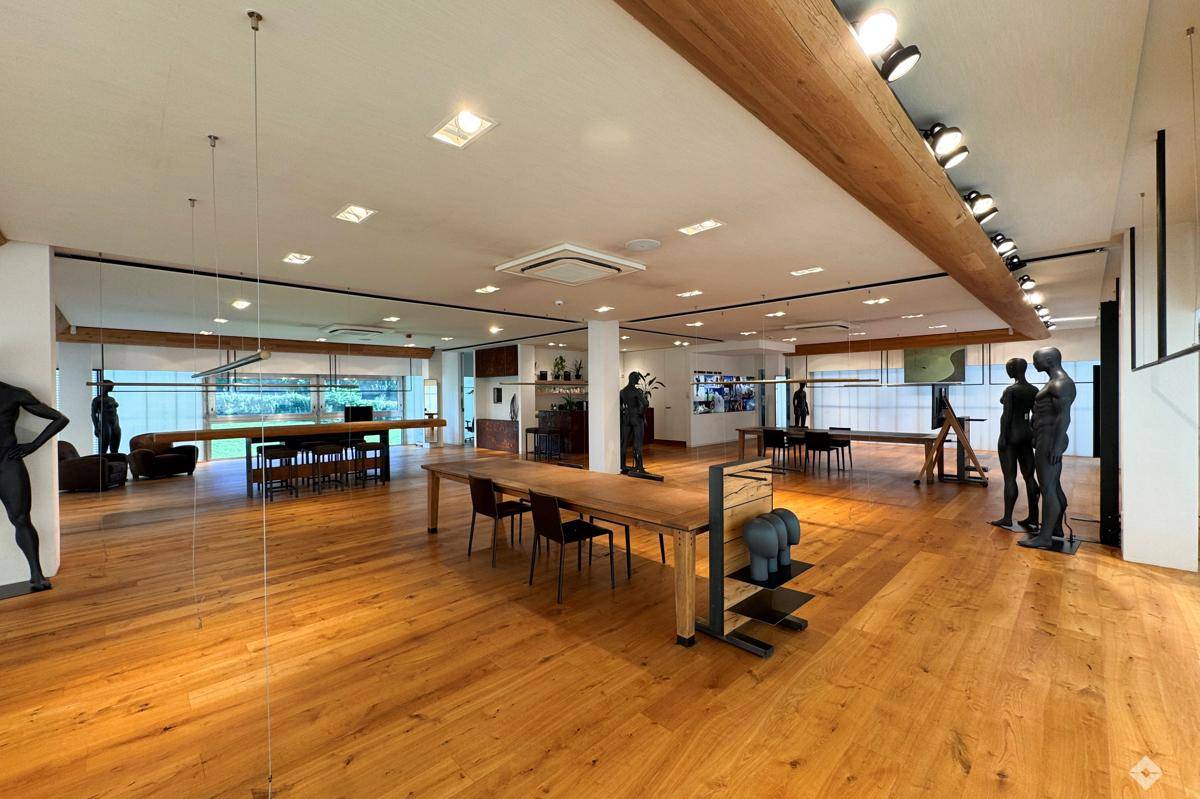 Geräumiger Verkaufsraum mit Holzboden, sichtbaren Holzbalken und modernen Präsentationsflächen.
