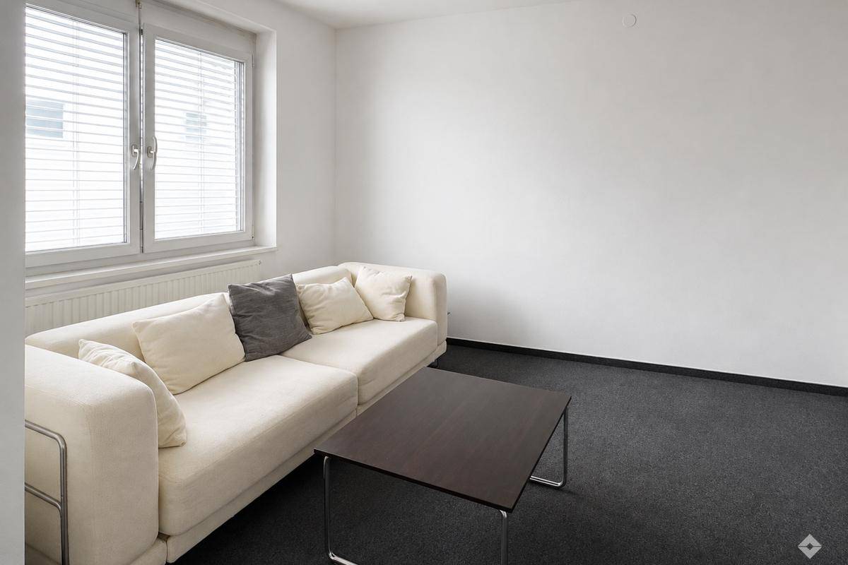 Gemütlicher Wartebereich oder Lounge mit Sofa, Couchtisch und Teppichboden.