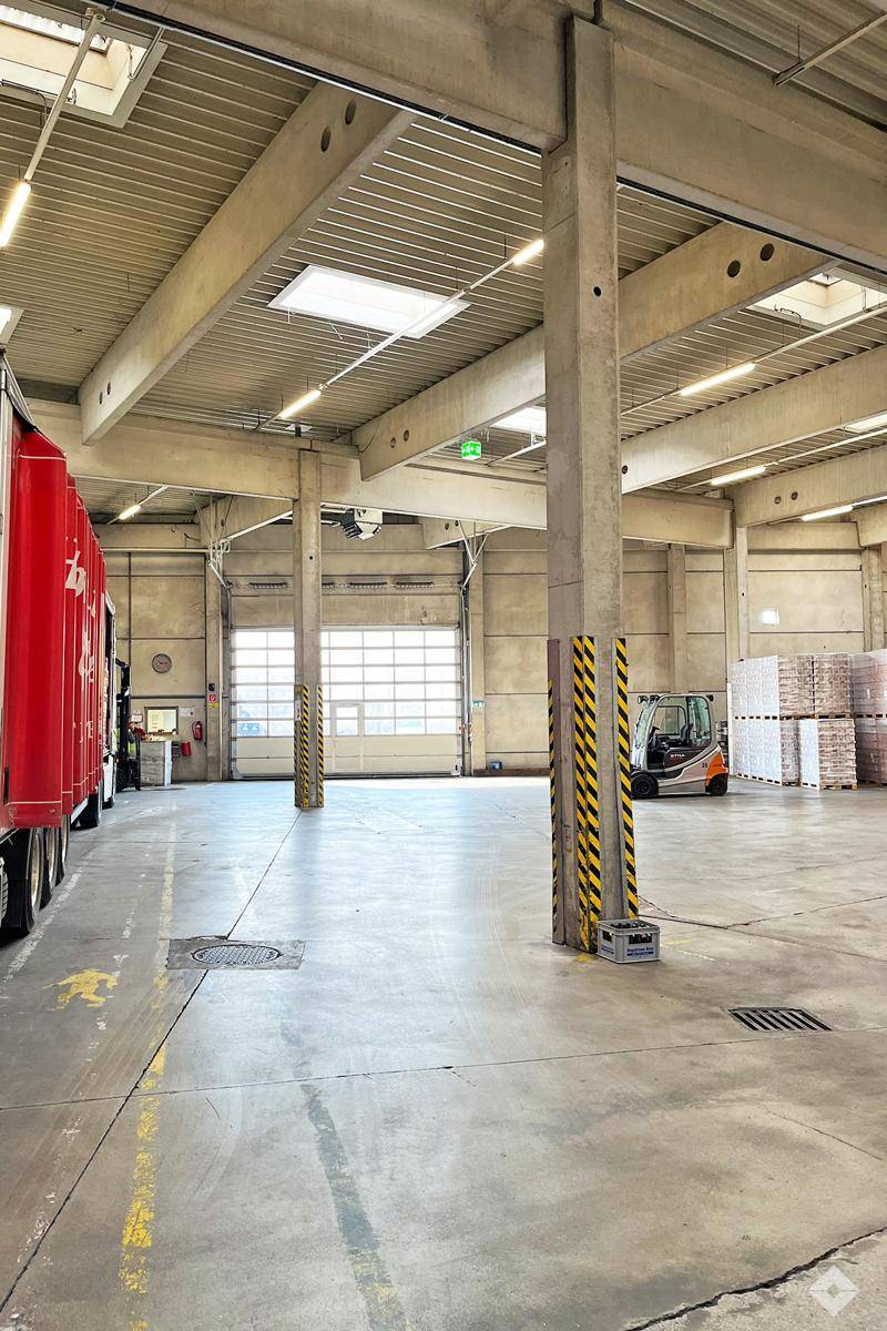 Geräumige Lagerhalle mit LKW-Zugang, robusten Säulen und Oberlichtern, optimiert für effiziente Logistikabläufe.