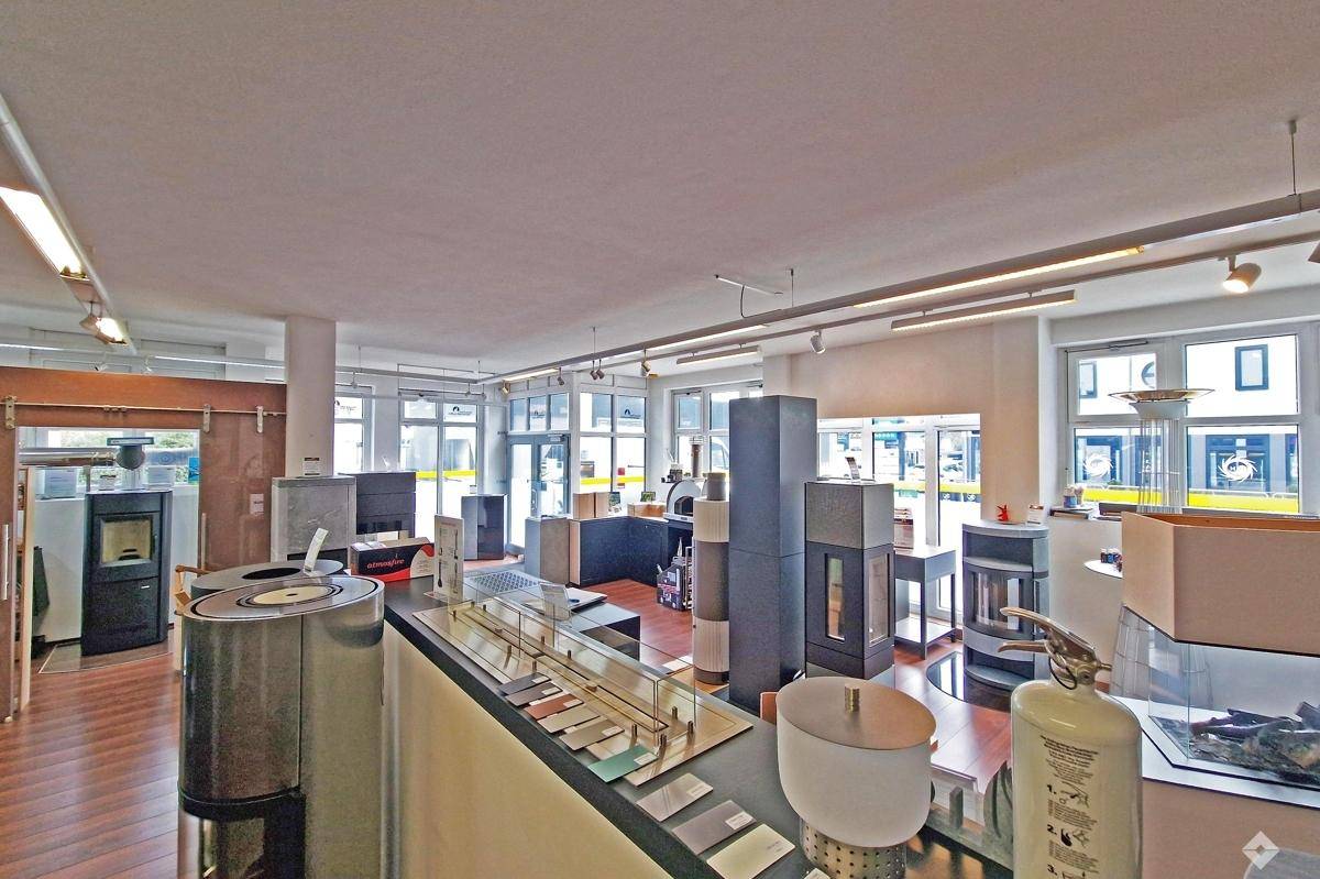 Weitläufiger Ausstellungsraum mit modernen Kaminöfen und großen Fensterfronten für viel Tageslicht.
