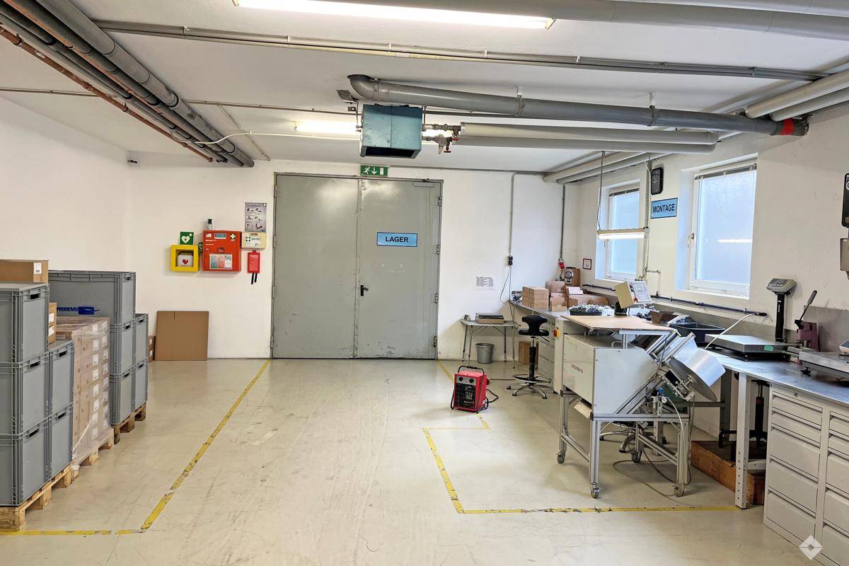 Lagerraum mit Betonboden, doppelter Metalltür und sichtbaren Rohren an der Decke.