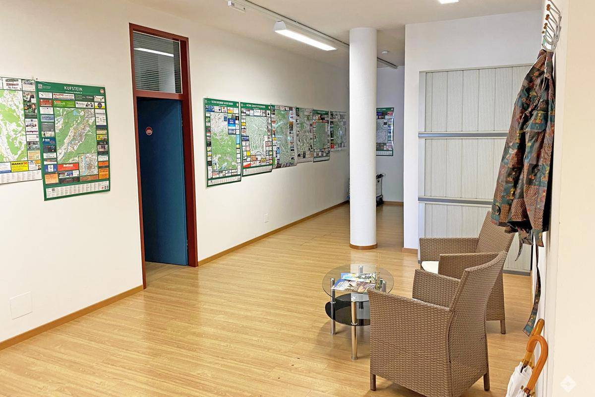 Einladender Empfangsbereich mit bequemen Korbsesseln, Glastisch und hellem Holzboden.