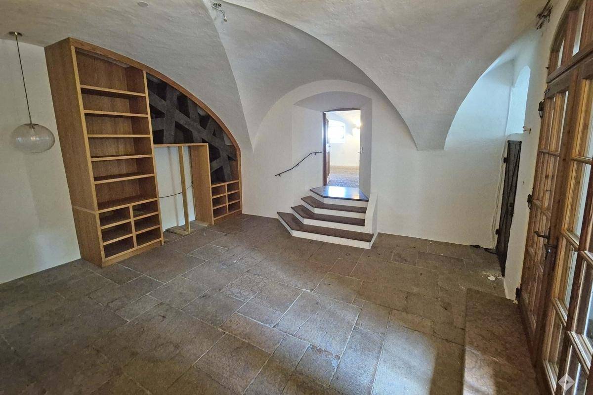 Historischer Flur mit Gewölbedecke, Steinfliesenboden und eingebauten Holzregalen.