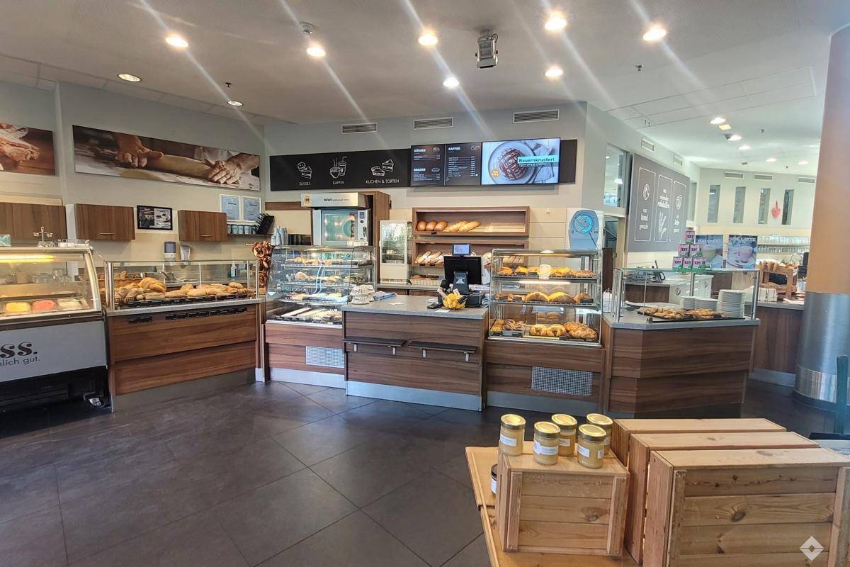 Bäckerei- und Cafébereich mit Auslagen für Backwaren und Holzmöbeln.