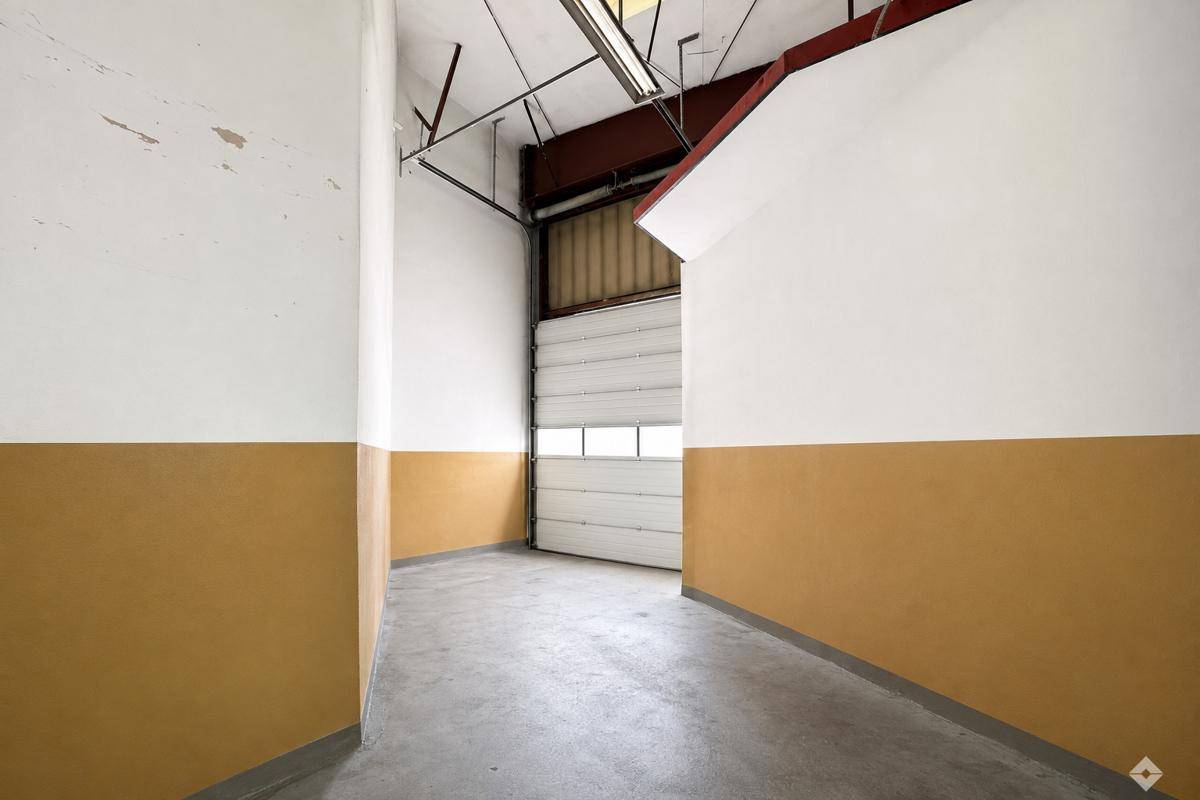 Innenansicht einer Halle mit Rolltor, hohen Wänden und einem Betonboden, bereit zur Nutzung.