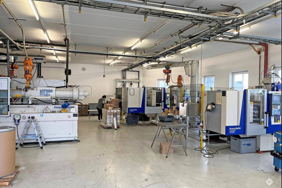 Große Produktionshalle mit mehreren Maschinen, hohen Decken und industrieller Beleuchtung.