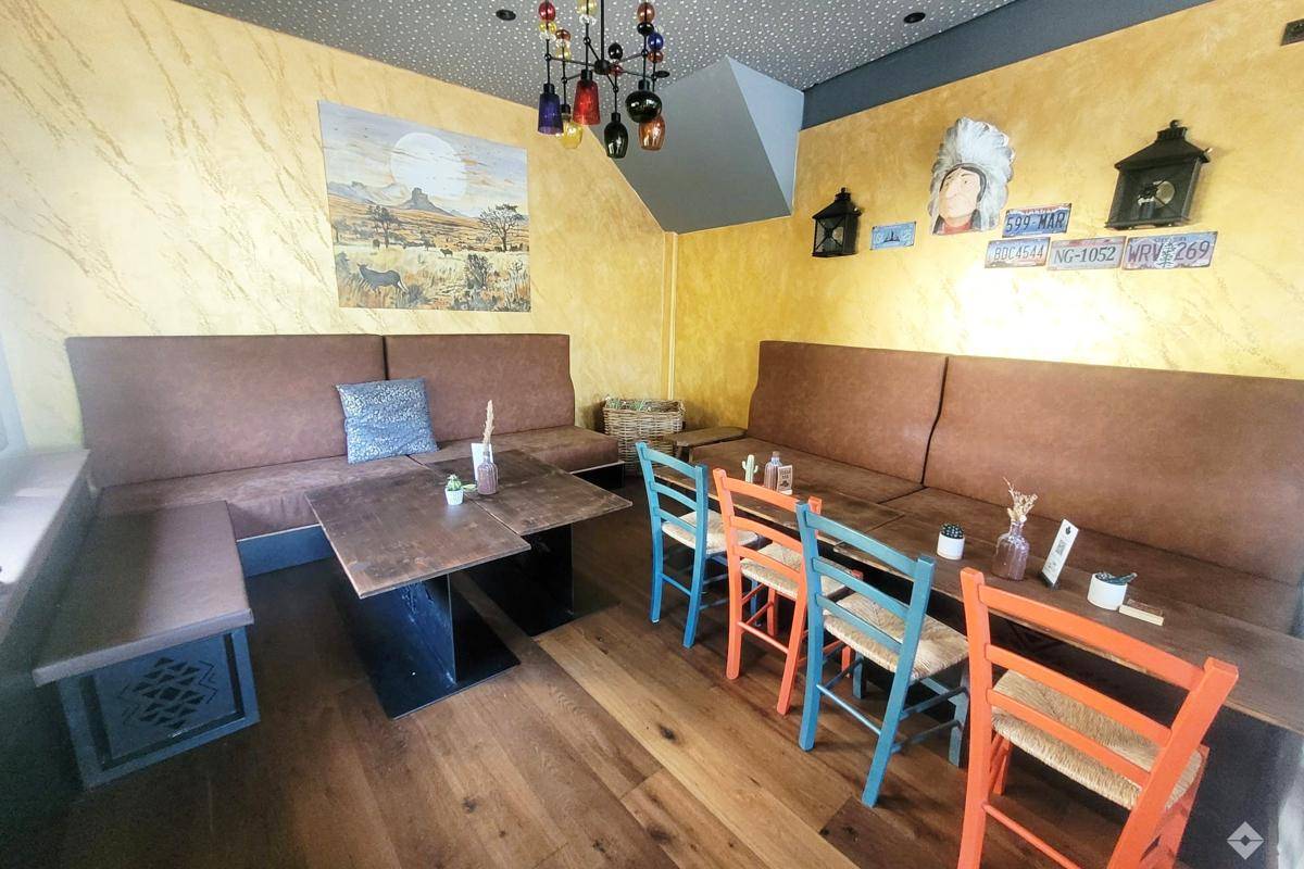Ein gemütlicher Essbereich mit langen Sitzbänken, Holztischen und bunten Stühlen in einem Restaurant.