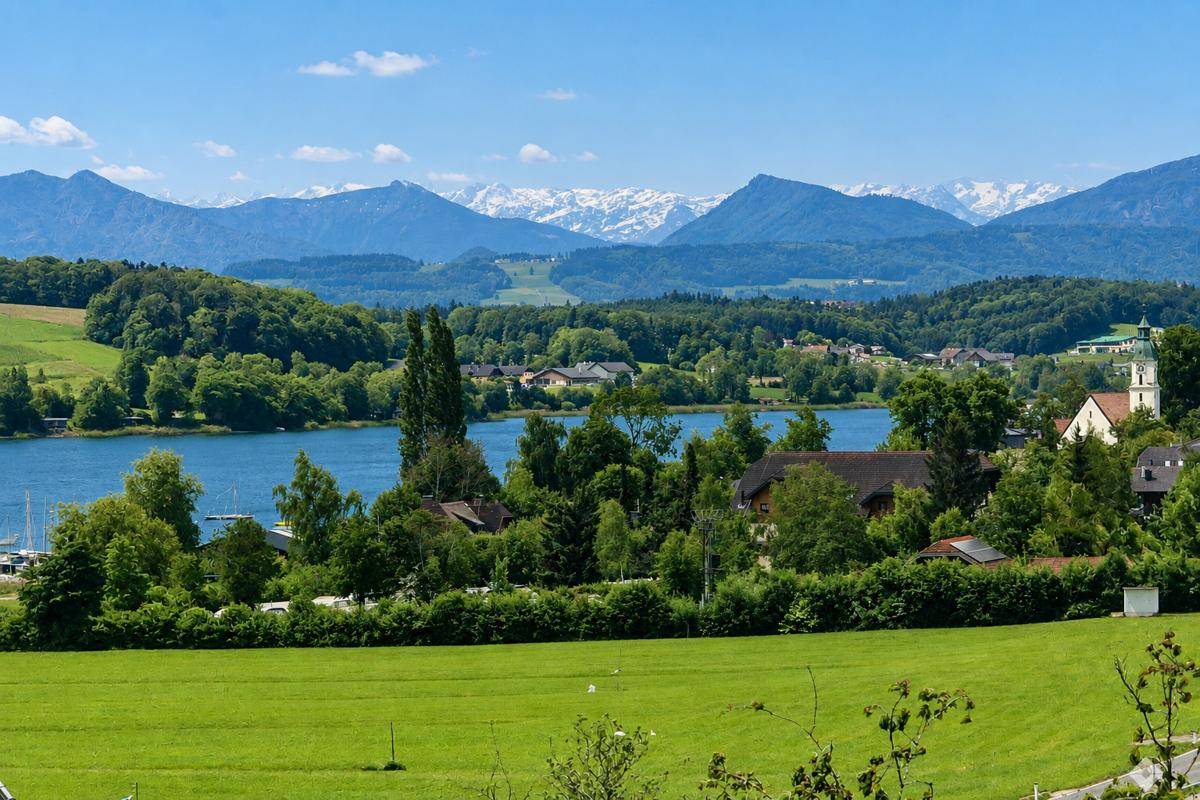 Malerischer Blick auf einen See mit umliegenden Bergen und grüner Landschaft.
