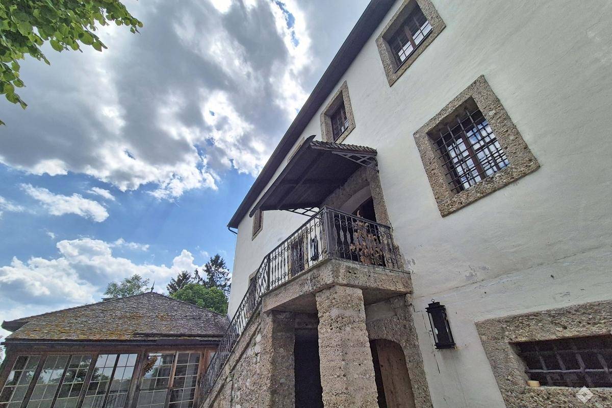 Historische Fassade mit schmiedeeisernem Balkon und Blick auf die umliegende Landschaft.
