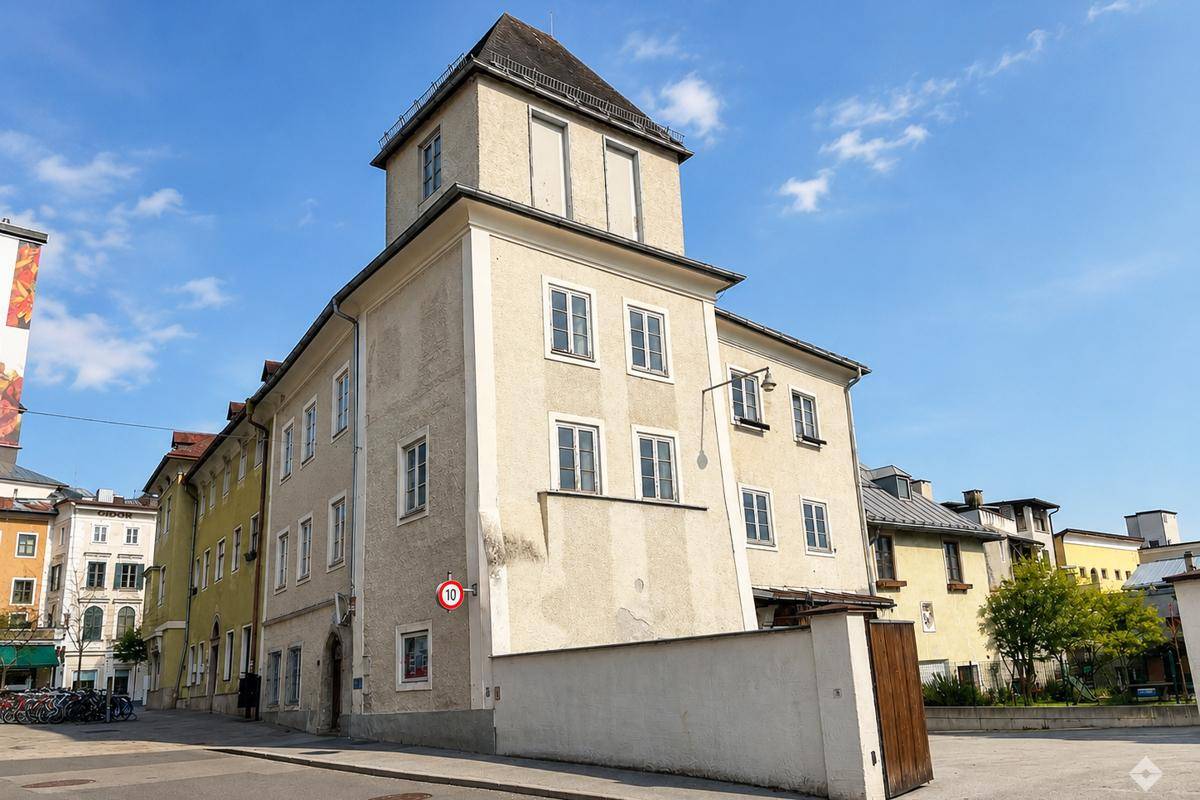 Historisches Gebäude mit markantem Turm und traditioneller Architektur in städtischer Umgebung.