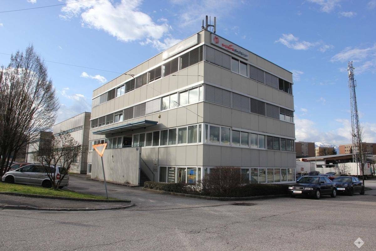 Gepflegtes Bürogebäude mit Jalousien an den Fenstern und Parkmöglichkeiten im Freien.