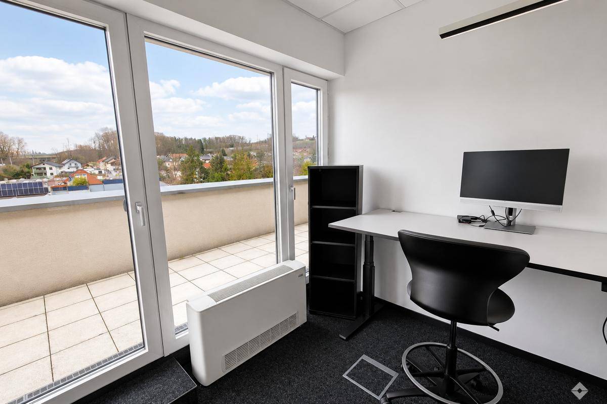 Helles Einzelbüro mit modernem Arbeitsplatz, Zugang zur Terrasse und Blick auf die Umgebung.