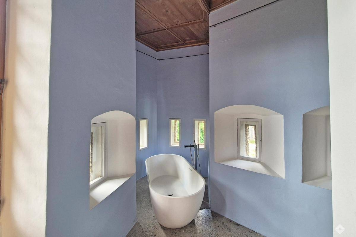 Modernes Badezimmer mit freistehender Badewanne, blauen Wänden und kleinen Fenstern.