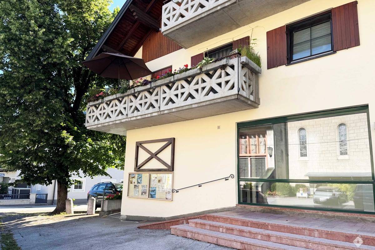Geräumiger, offener Innenraum mit Holzfußboden, einer Wendeltreppe und großen Fenstern.