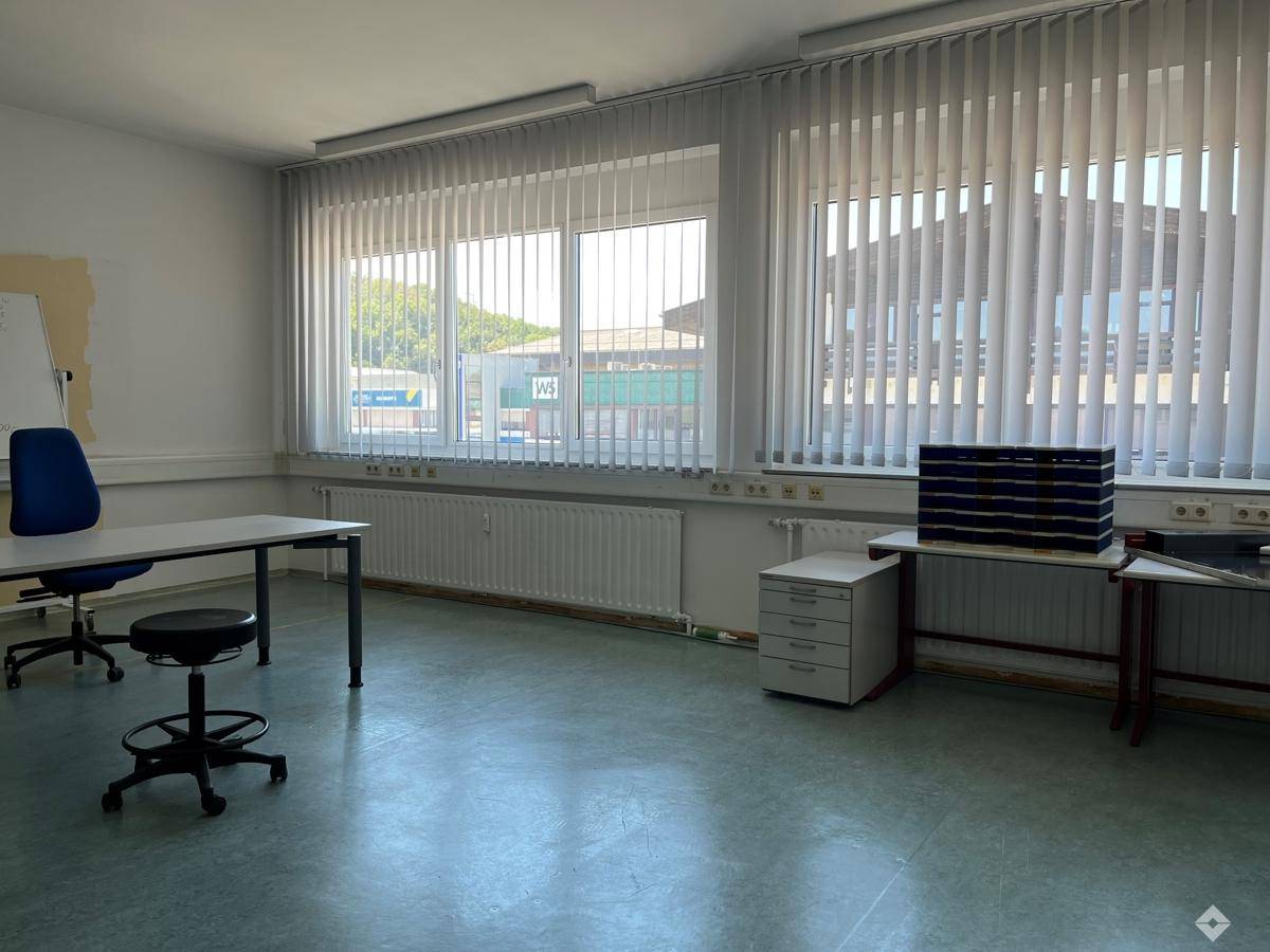 Großes, helles Büro mit zwei Fensterfronten, vertikalen Jalousien und viel Platz für Arbeitsplätze.