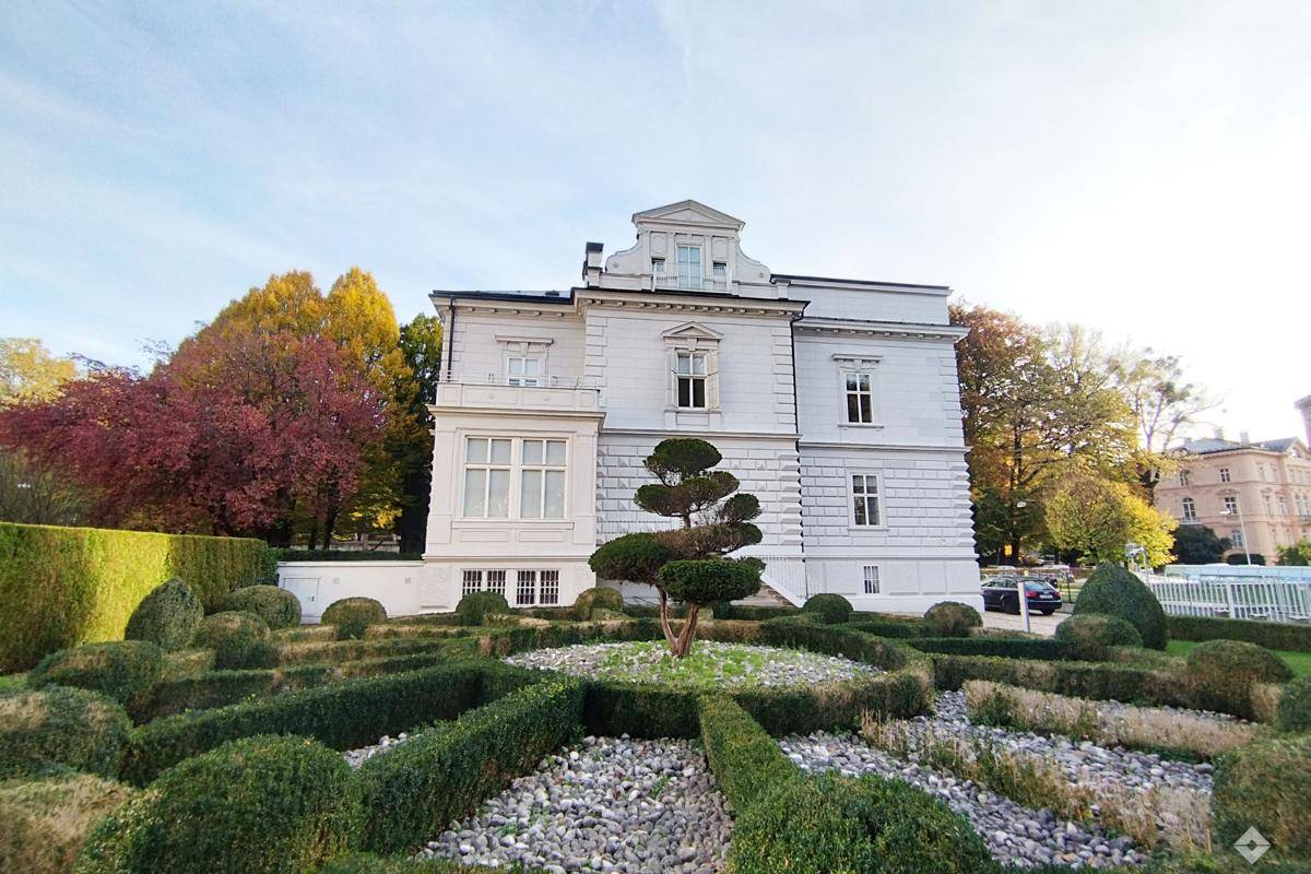Eindrucksvolles klassisches Gebäude mit weißer Fassade und einem gepflegten, kunstvoll gestalteten Gartenbereich.