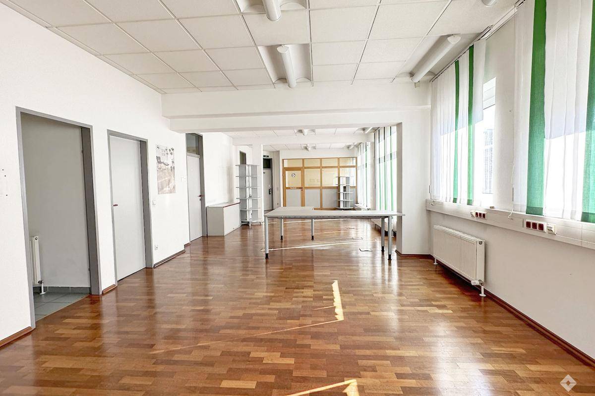Langer Flur oder offener Bürobereich mit Holzparkettboden und natürlichem Lichteinfall.