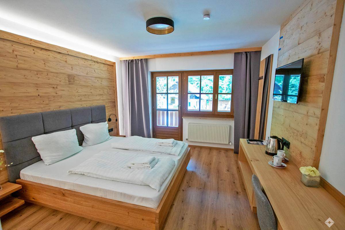 Gemütliches Schlafzimmer mit Holzwänden, Doppelbett und Zugang zu einem Außenbereich.