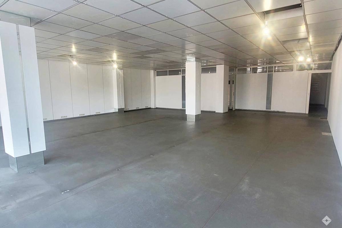 Großer, leerer Gewerberaum mit Betonboden, abgehängter Decke und Säulen, bereit für den Ausbau.