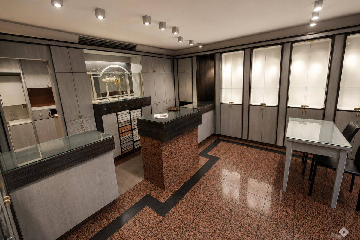 Geräumiger Verkaufsraum mit zahlreichen beleuchteten Vitrinen, Theken und gemustertem Fliesenboden.