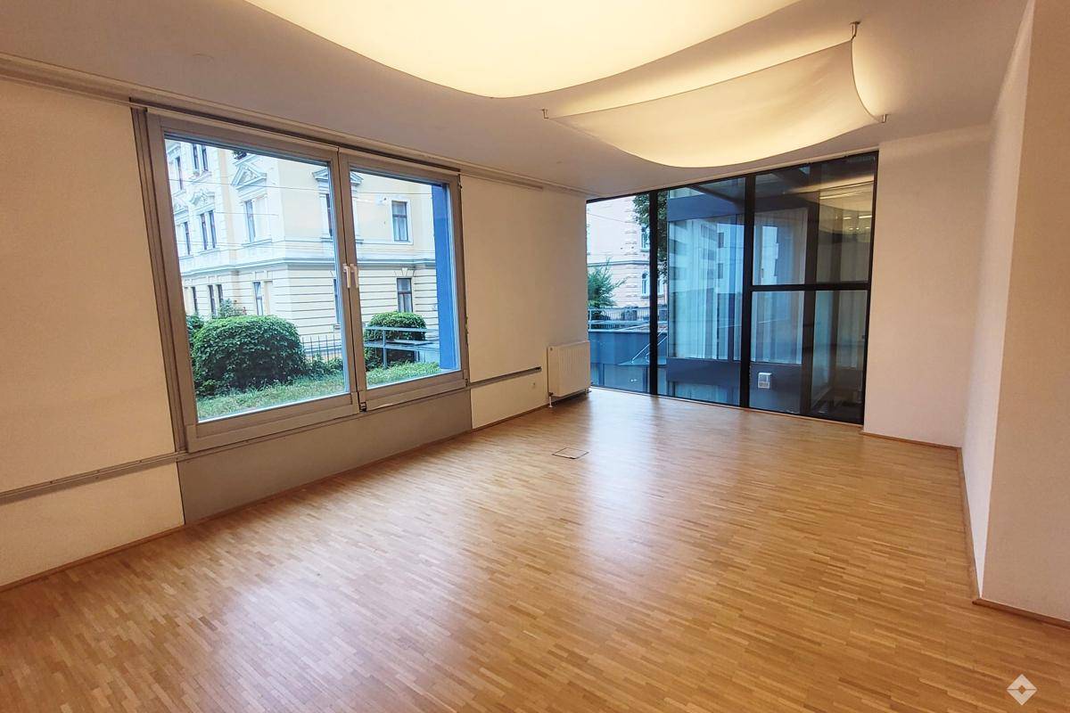 Großzügiger Wohnbereich mit Holzboden und großen Glasflächen, die viel Helligkeit in den Raum bringen.