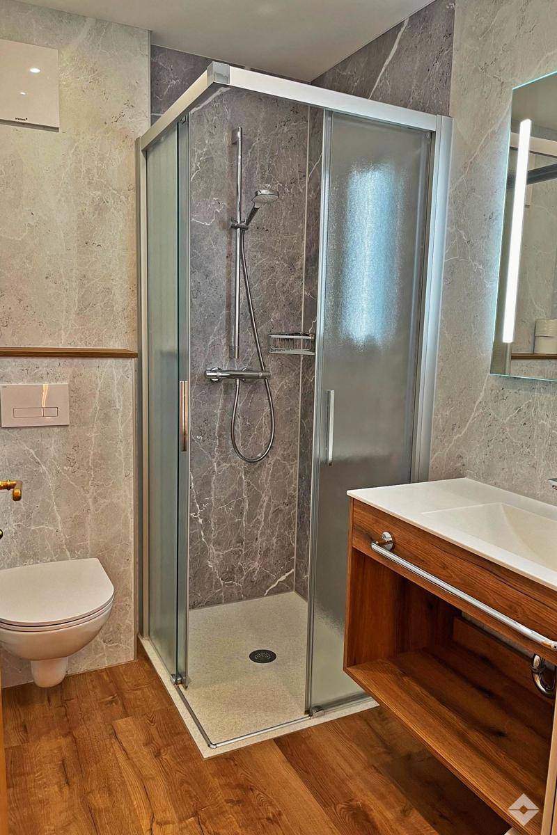 Modernes Badezimmer mit Duschkabine, Wand-WC und stilvollem Holzwaschtisch.