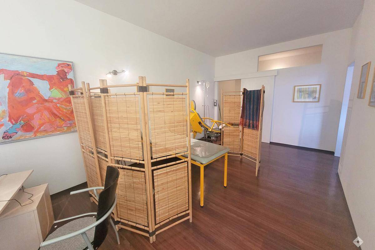 Büroraum mit Holzboden, Raumteilern aus Bambus und farbenfrohem Kunstwerk an der Wand.