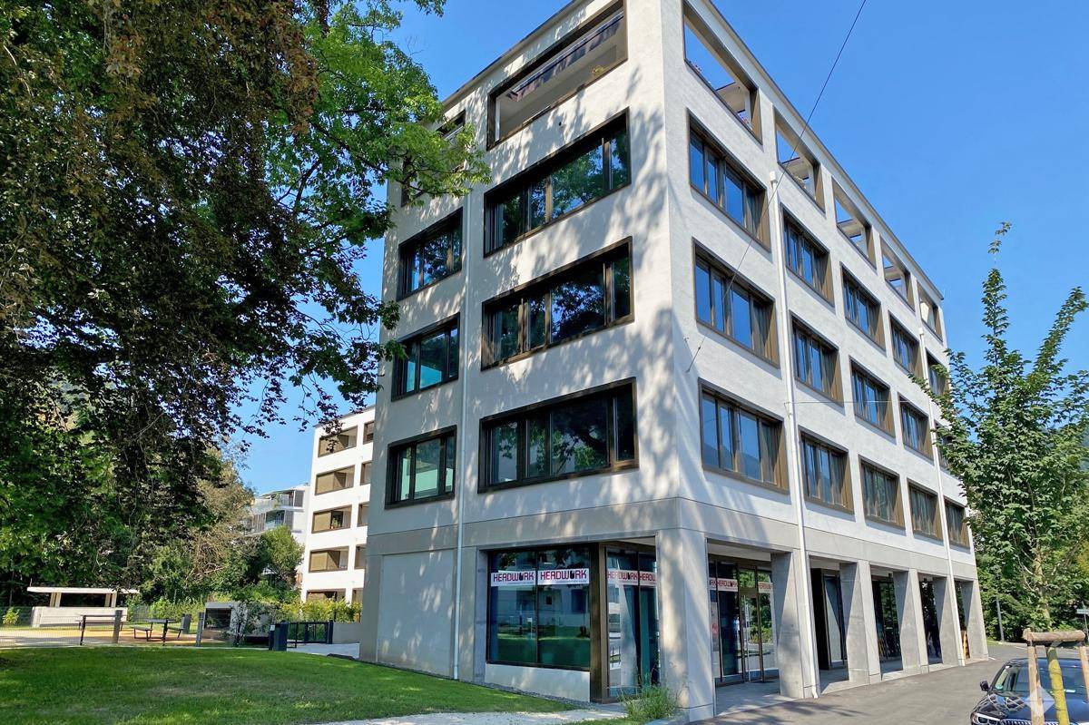 Modernes Geschäftsgebäude mit großen Glasflächen und umliegender Grünfläche.
