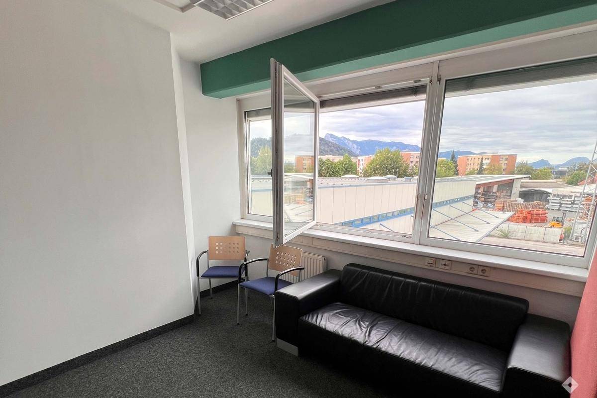Gemütlicher Wartebereich oder kleines Büro mit Ledersofa und weitem Bergblick durch große Fenster.