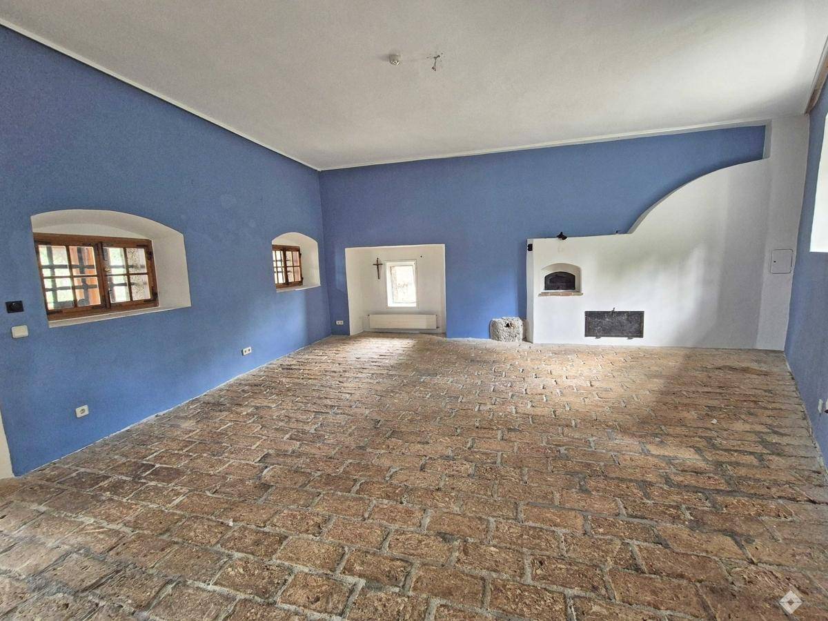 Geräumiger Raum mit blauen Wänden, rustikalem Ziegelboden und einem traditionellen Kamin.