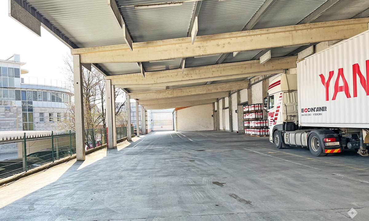Überdachter Außenbereich für LKW-Beladung mit Betonstützen und Zufahrt, ideal für Logistik.