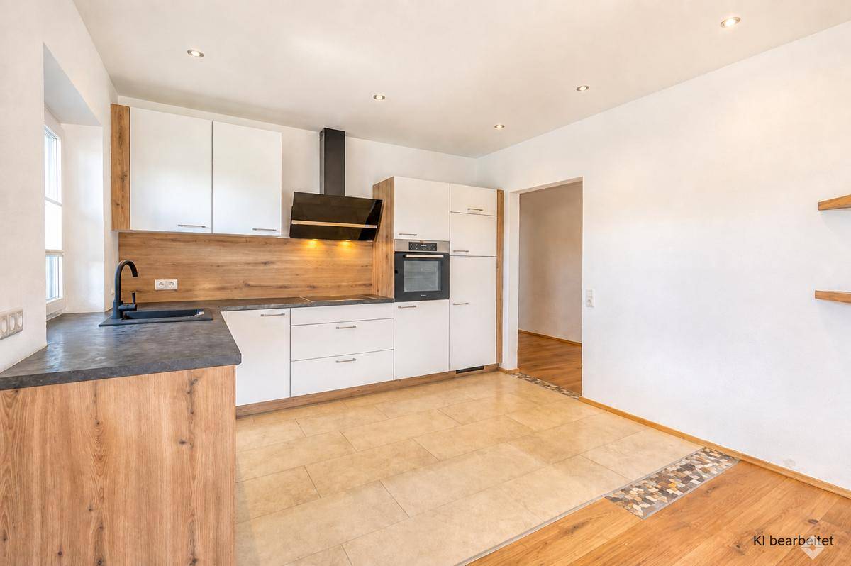 Moderne Küche mit weißen Schränken, Holzdetails, integrierten Geräten und Fliesenboden.