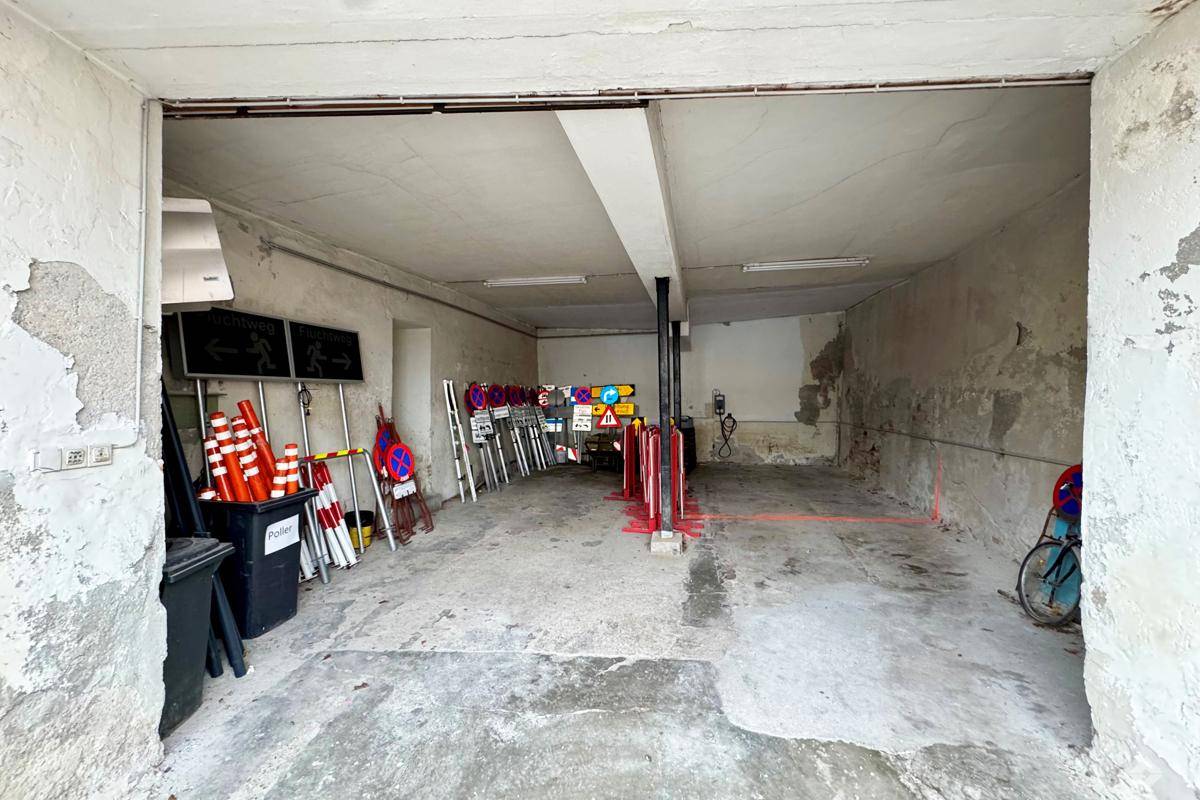 Geräumige Garage mit Betonboden und viel Stauraum, ideal für Fahrzeuge und Lagerung.