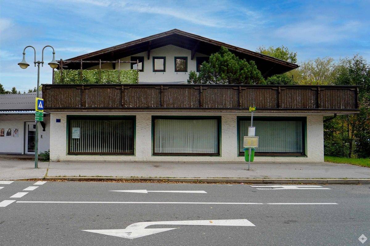 Gebäude mit Geschäftsflächen im Erdgeschoss und Wohnungen darüber, mit einem Balkon und traditionellem Dach.