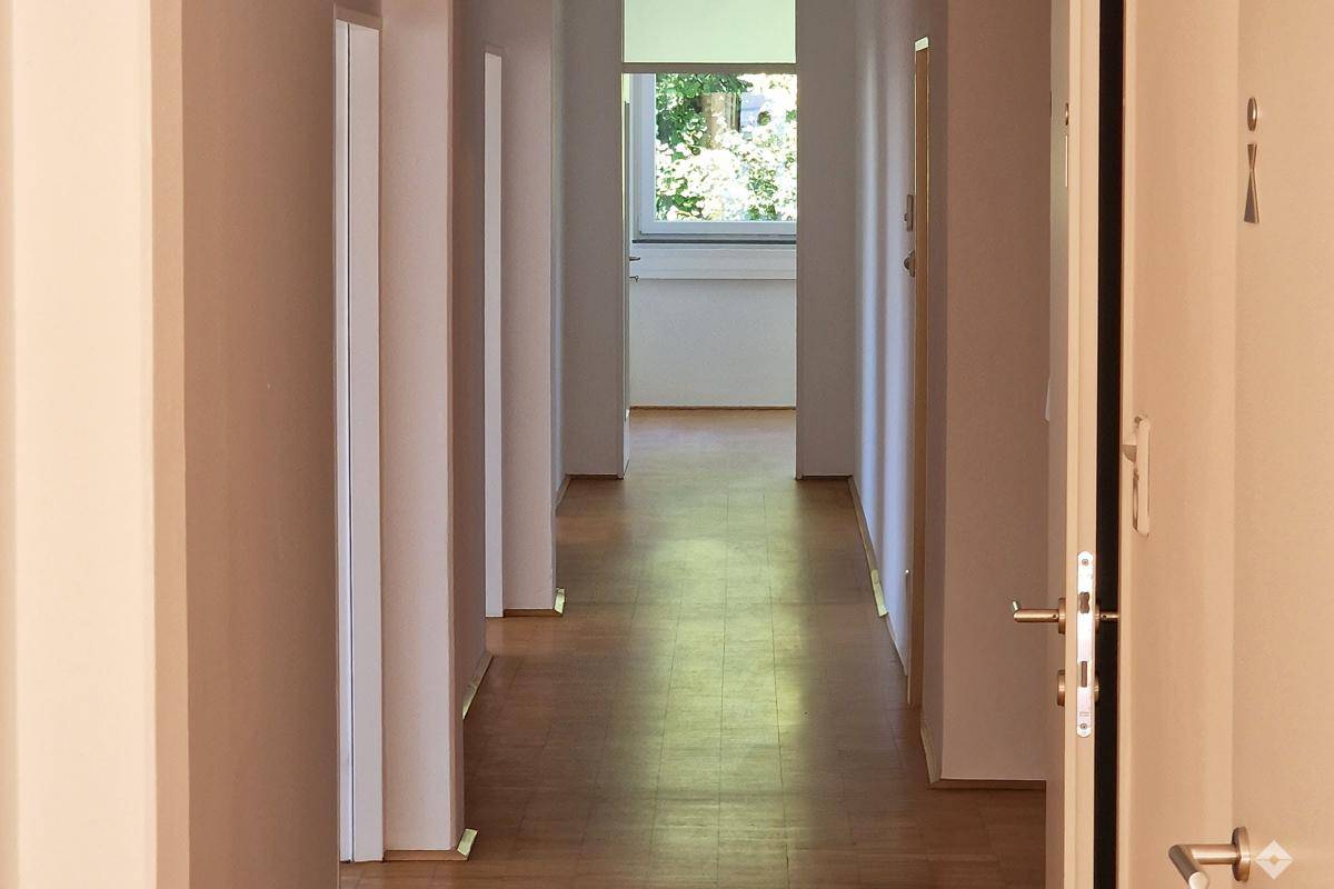 Langer, heller Flur mit Holzboden und mehreren Türen, der zu weiteren Räumen führt.