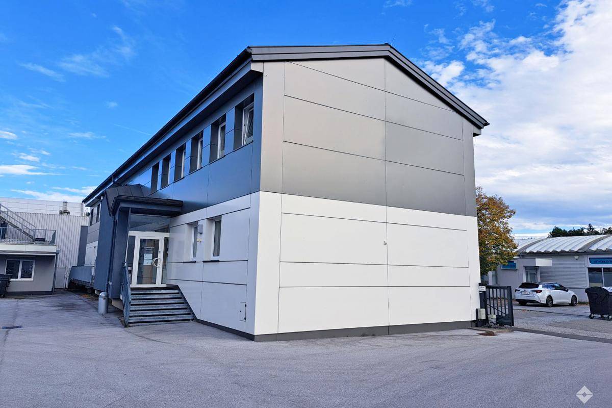 Modernes Geschäftsgebäude mit grauer und weißer Fassade unter blauem Himmel.