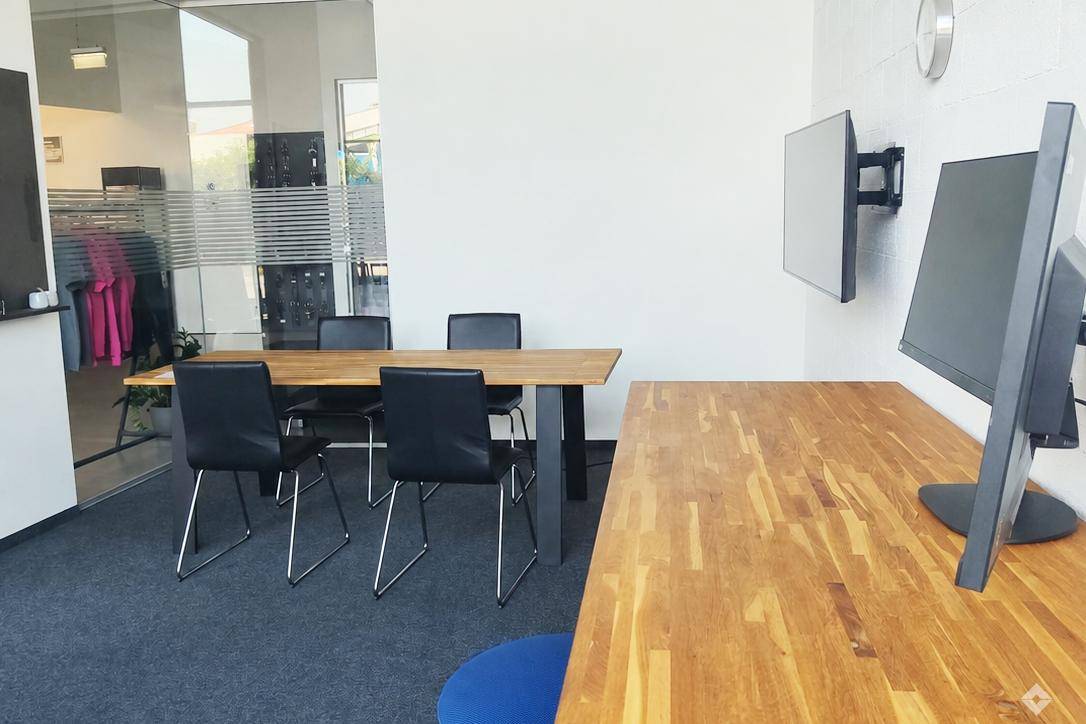 Modernes Büro mit Konferenztisch, Bürostühlen und einem Arbeitsplatz, getrennt durch eine Glaswand.