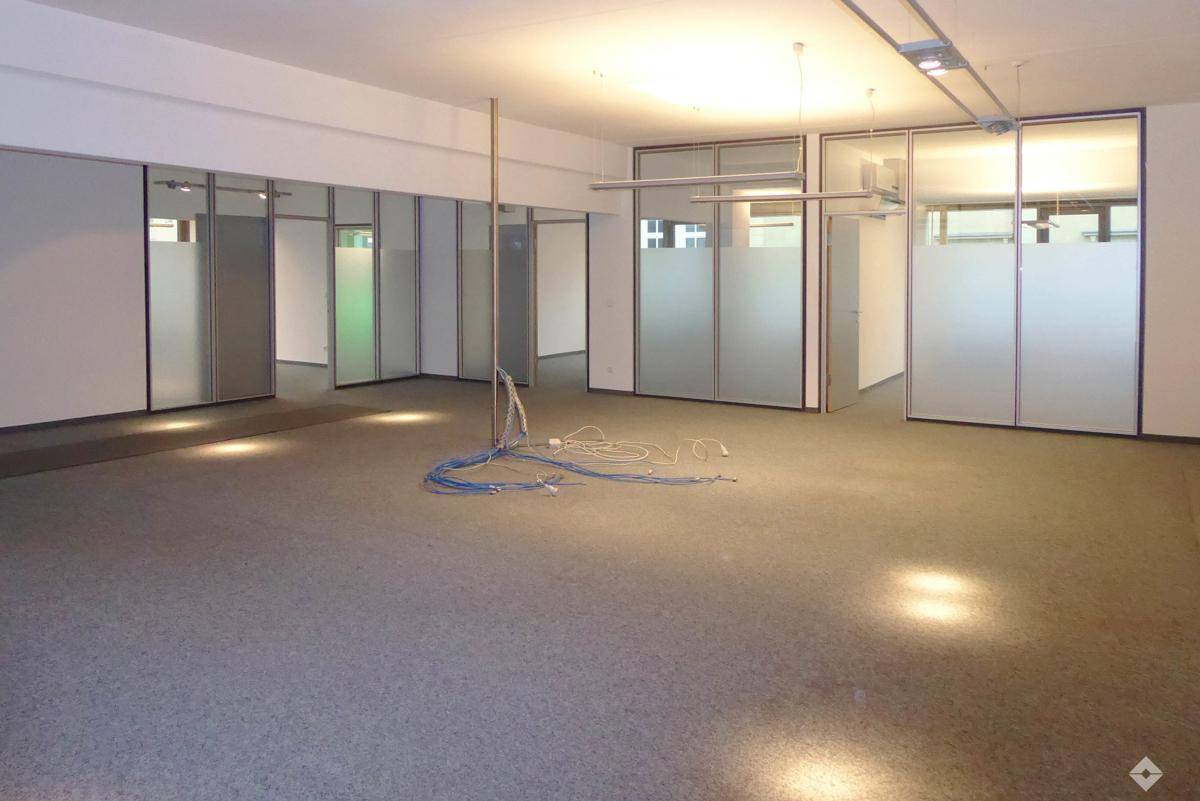 Helles Büro mit großen Fenstern und Blick auf die umliegenden Gebäude, ausgestattet mit Heizkörpern.