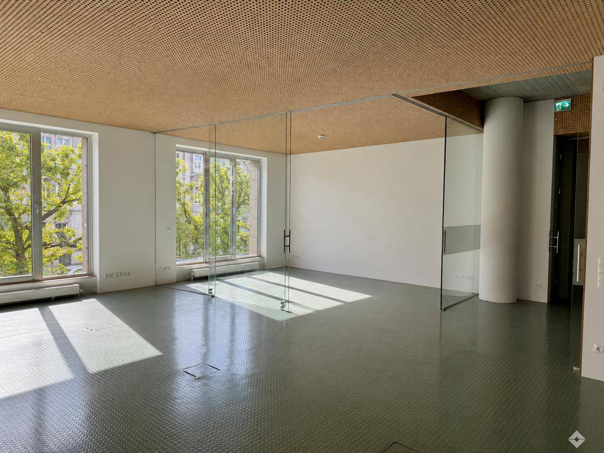 Heller Büroraum mit großen Fenstern, die viel Tageslicht hereinlassen und einen Blick ins Grüne bieten.