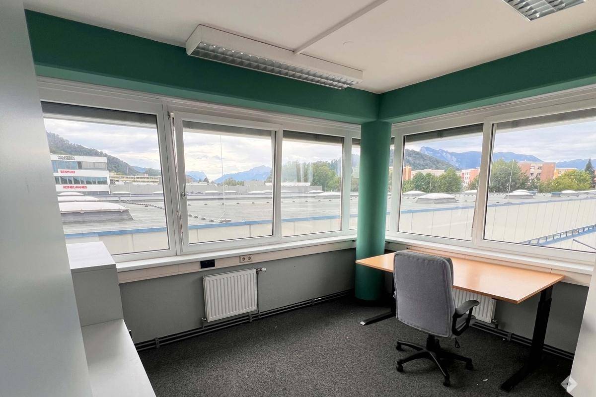 Helles Eckbüro mit Schreibtisch, Bürostuhl und weitem Blick über die Dächer der Stadt.