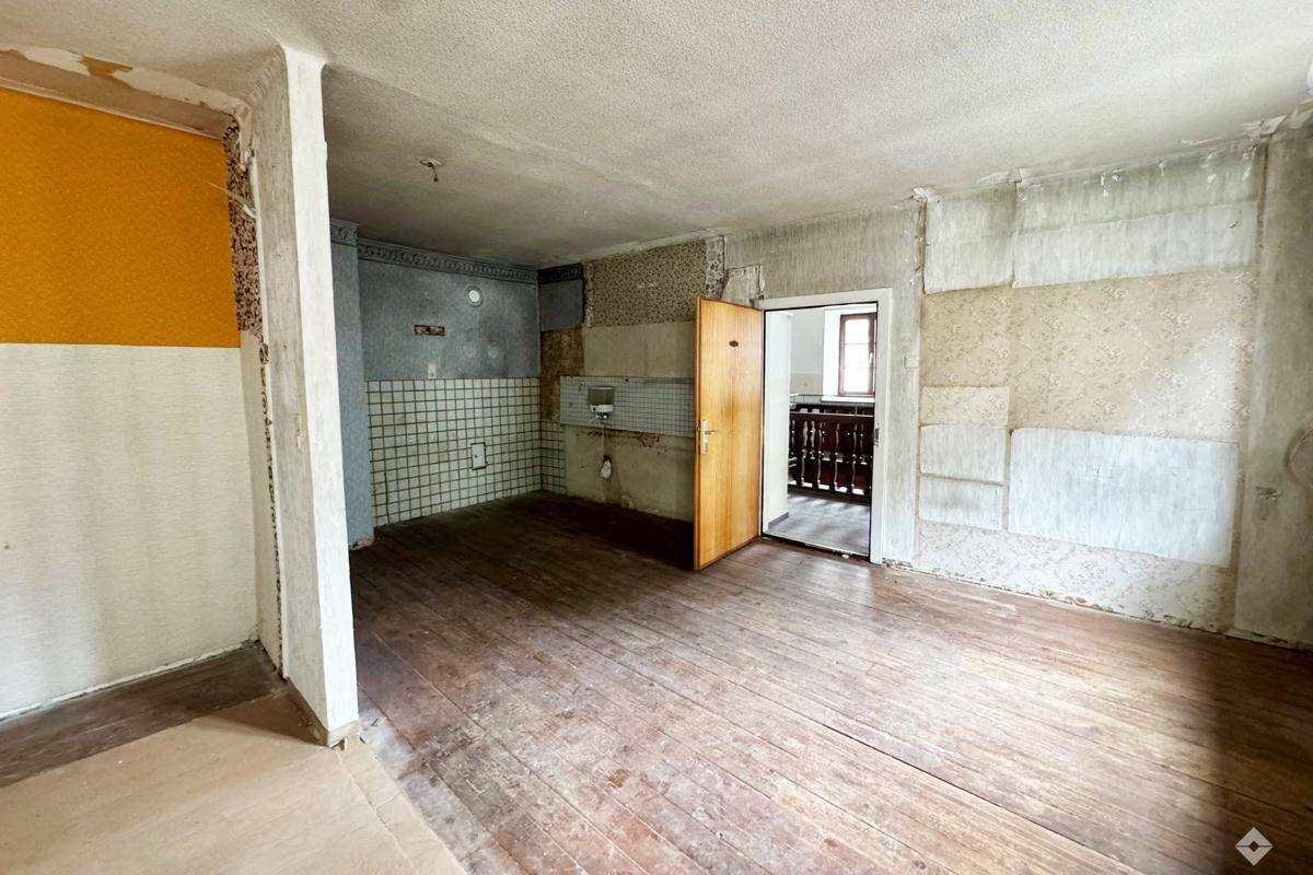 Renovierungsbedürftige Küche mit alten Fliesen und Holzdielenboden, bereit für eine Neugestaltung.