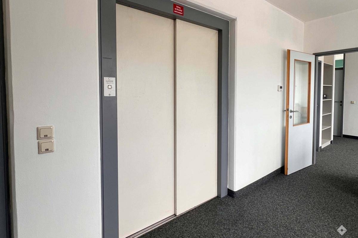 Heller Flur mit Aufzug und Zugang zu weiteren Büroräumen, ausgestattet mit Teppichboden.