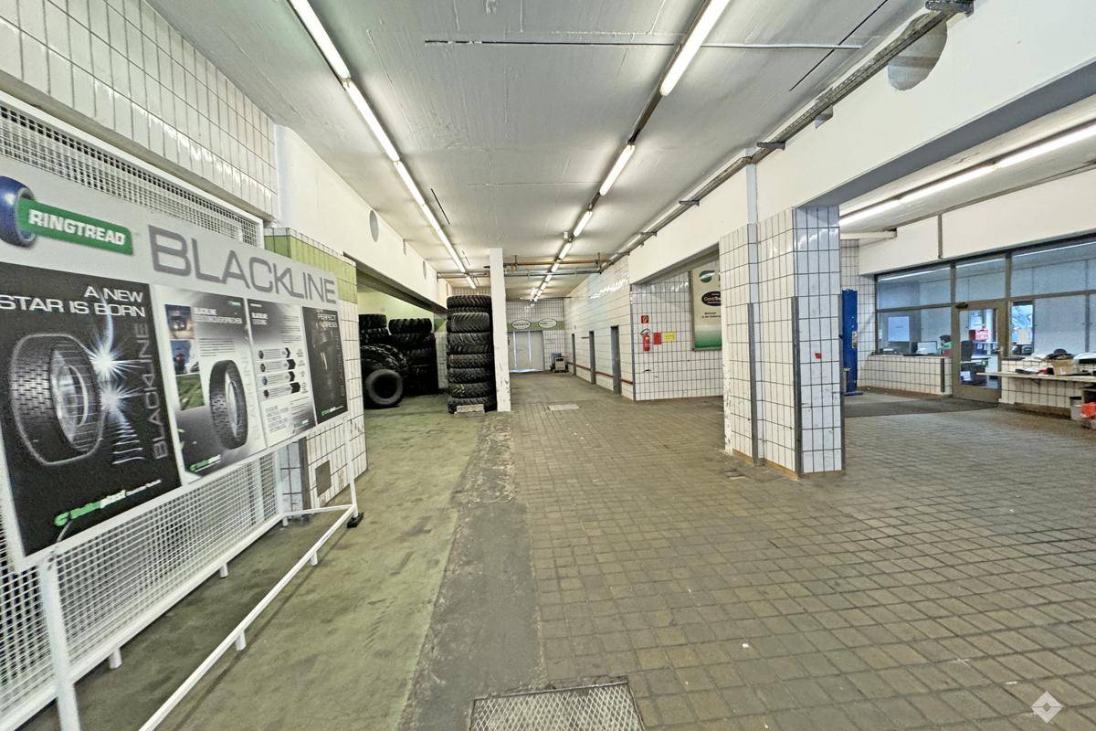 Weitläufiger Lagerraum mit gefliesten Wänden, Betonboden und Auslagen für Reifenprodukte.