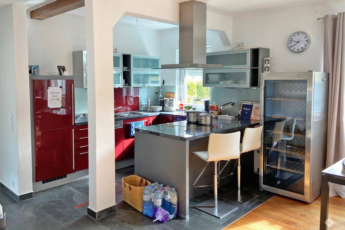 Moderne Küche mit roten und grauen Schränken, einer Kücheninsel und integrierten Geräten.