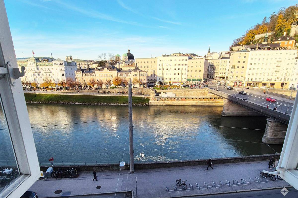 Weitläufiger Blick auf die Salzach und die historische Stadtkulisse von Salzburg an einem sonnigen Tag.