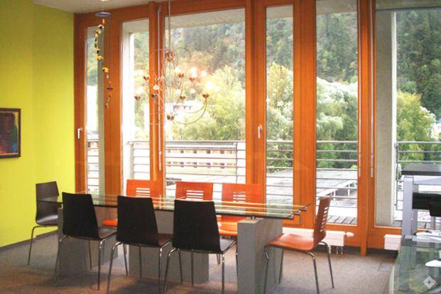 Helles und geräumiges Büro mit mehreren Arbeitsplätzen, großen Fenstern und Pflanzen.